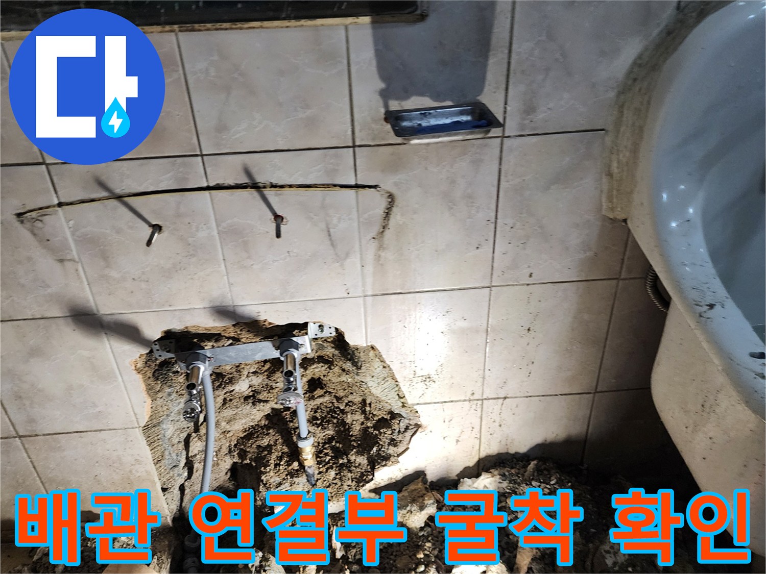 세면대 아래 벽면 타일을 제거하여 노출시킨 배관 및 주변 토사