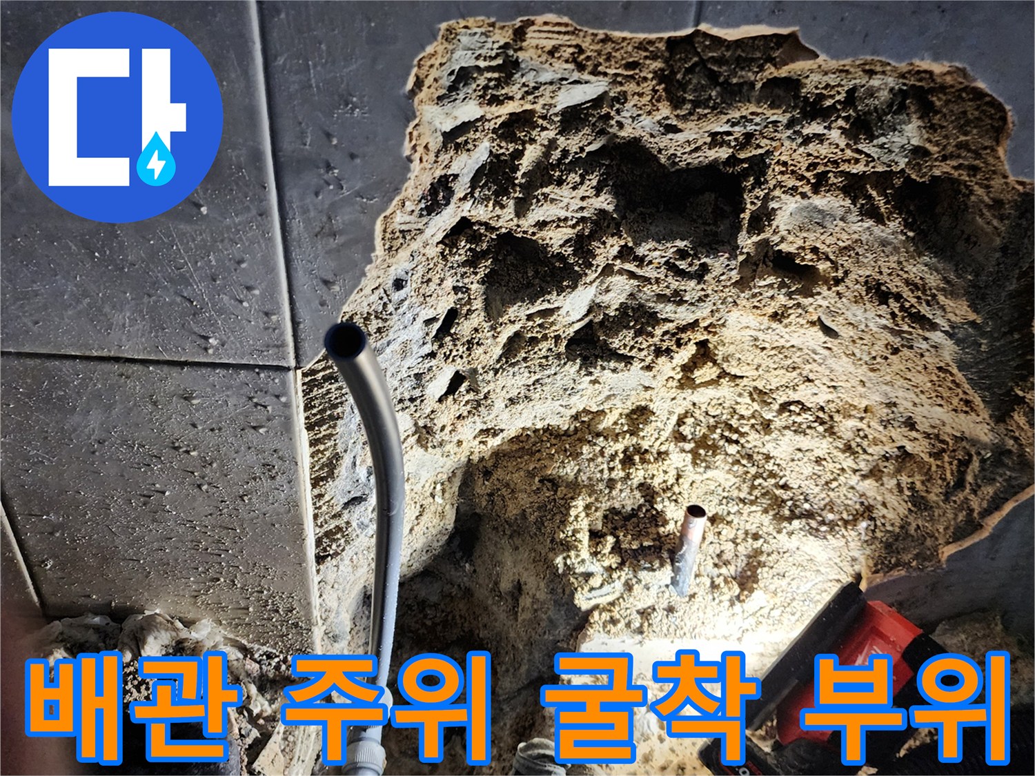 파쇄된 타일 사이로 보이는 하수관과 작업 도구들