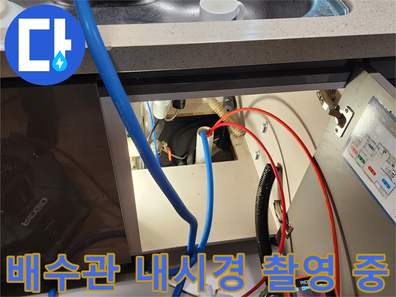 싱크대 하부장 아래 복잡한 배관 사이로 내시경 선을 투입하는 장면