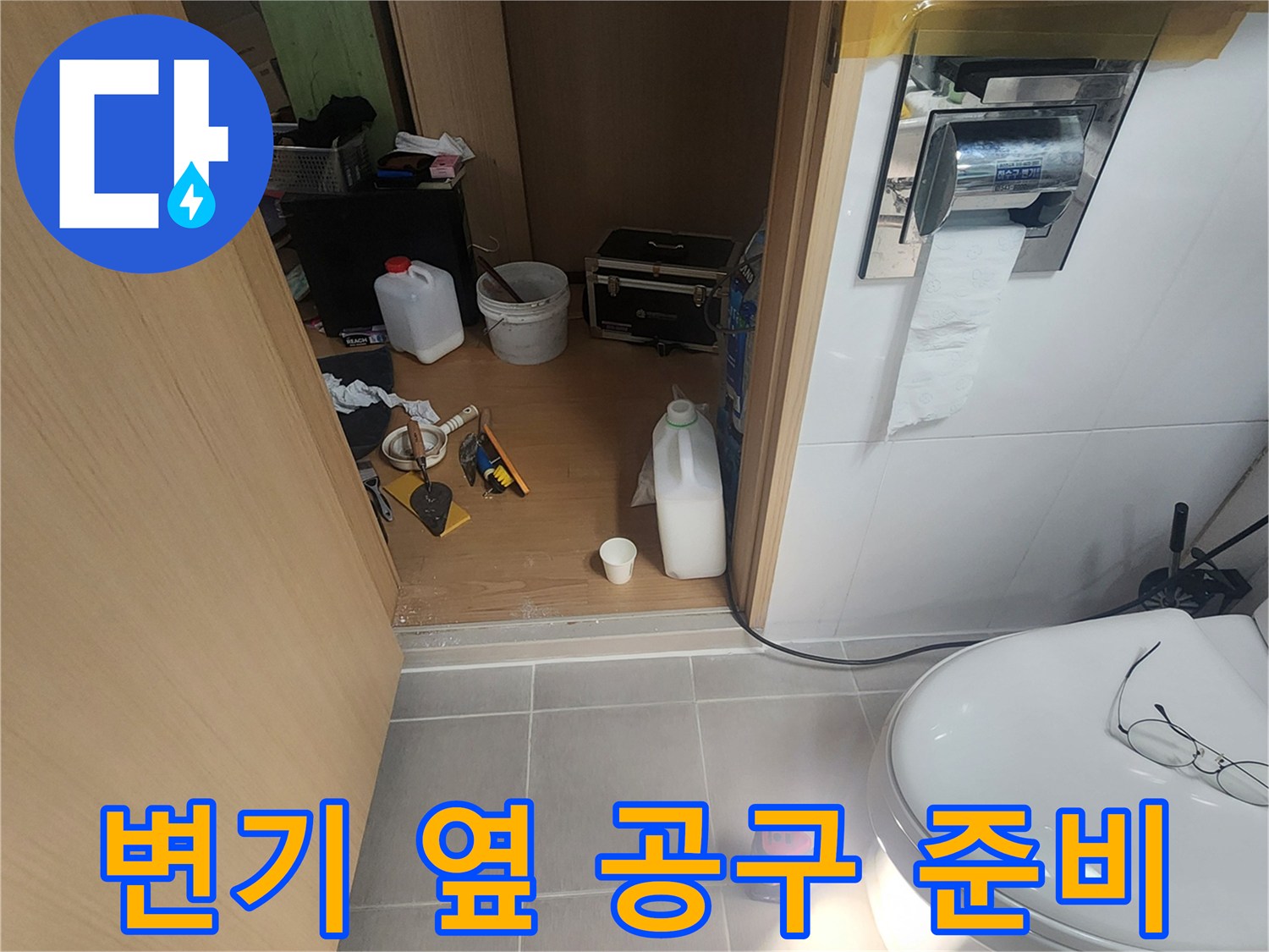 화장실 바닥에 놓인 작업용 도구와 배관 보수용 자재들