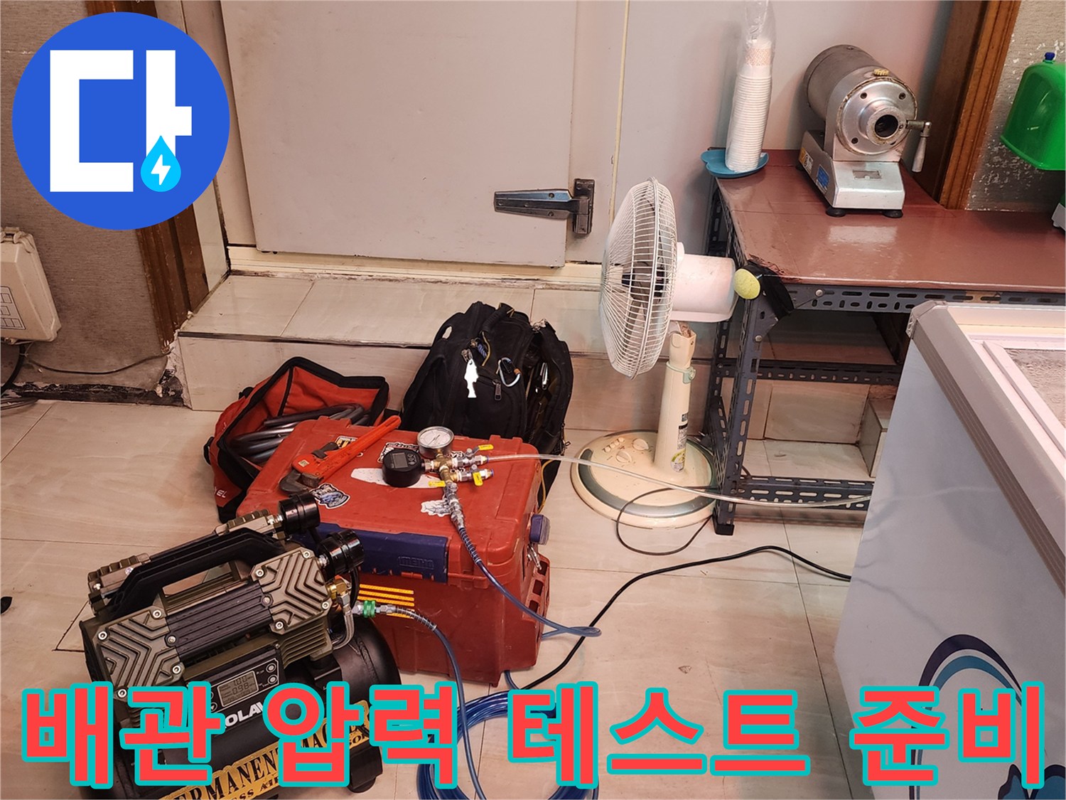 배관의 기밀 상태를 확인하기 위해 연결된 파란색 호스와 컴프레서