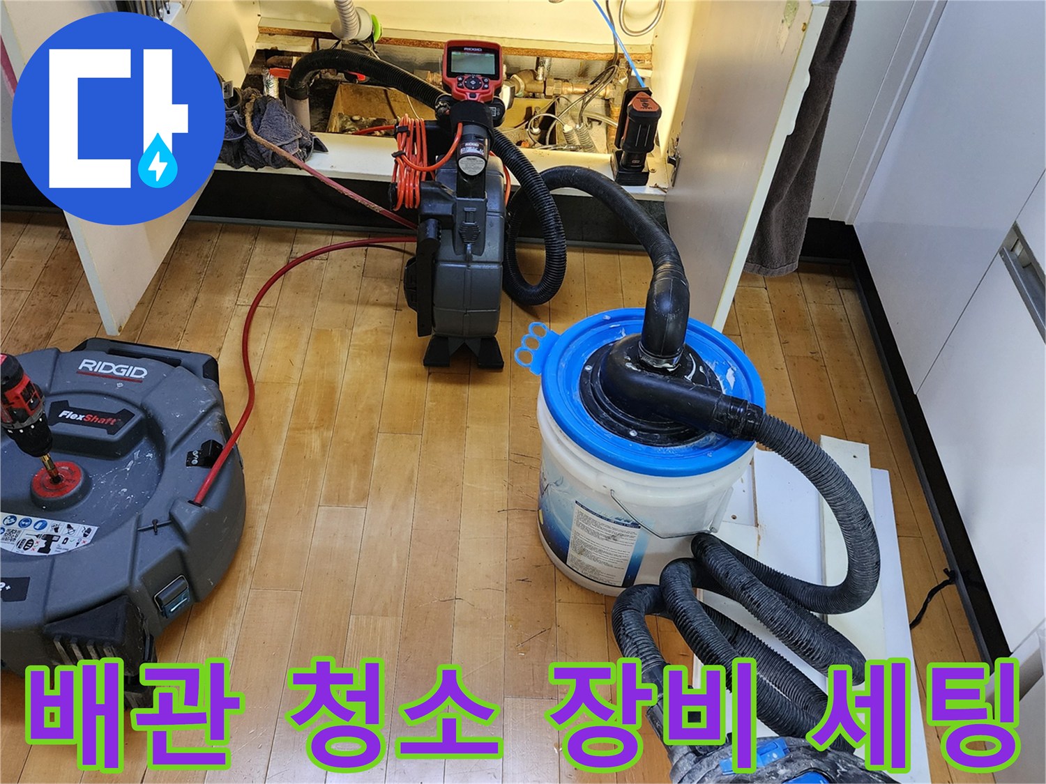 싱크대 하부장 아래 설치된 배관 스케일링 및 흡입 장비의 모습