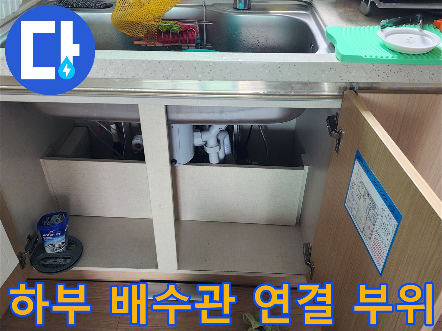 주방 싱크대 아래쪽의 백색 배관 및 연결 호스 상세 이미지입니다.