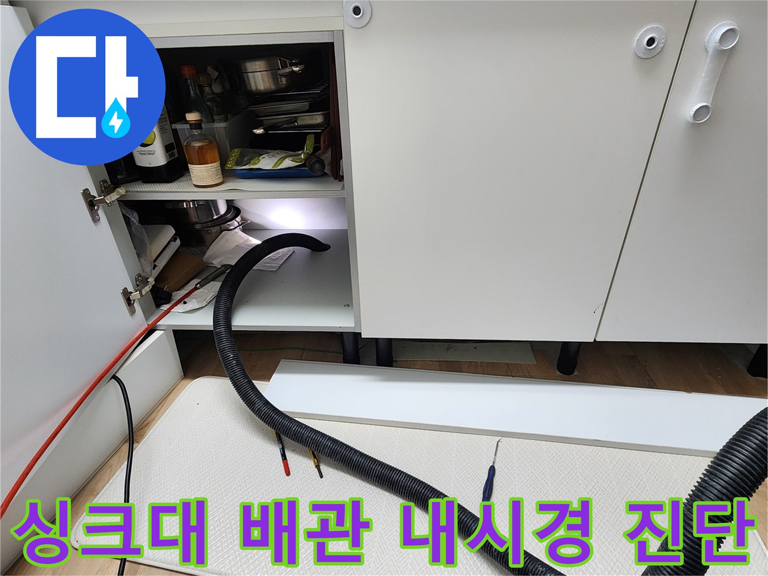싱크대 하부 배관 내부 점검을 위해 유연한 내시경 카메라를 투입하는 모습
