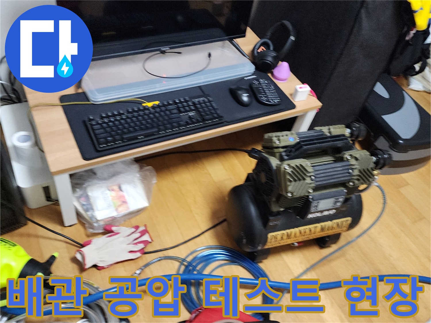 거실 바닥에 배치된 콤프레샤와 파란색 에어 호스