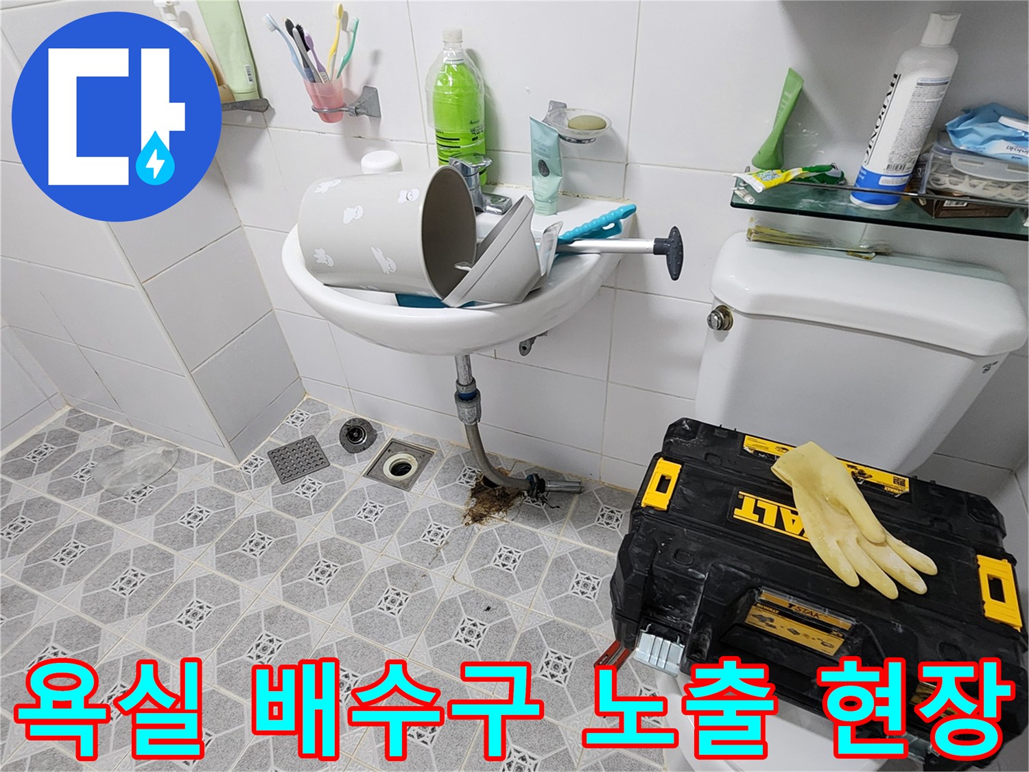 배수구 주변의 드러난 배관과 작업용 공구함 및 자재들