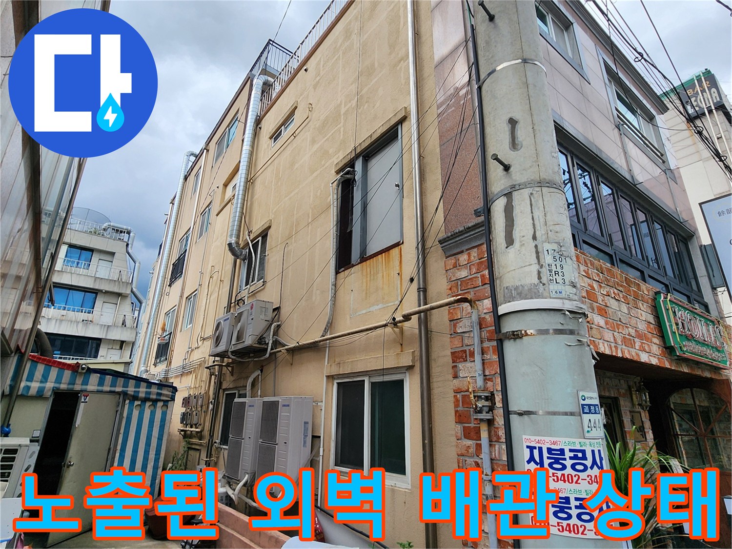 건물 외부 벽면에 설치된 금속 배관과 에어컨 연결 부위의 전체적인 모습