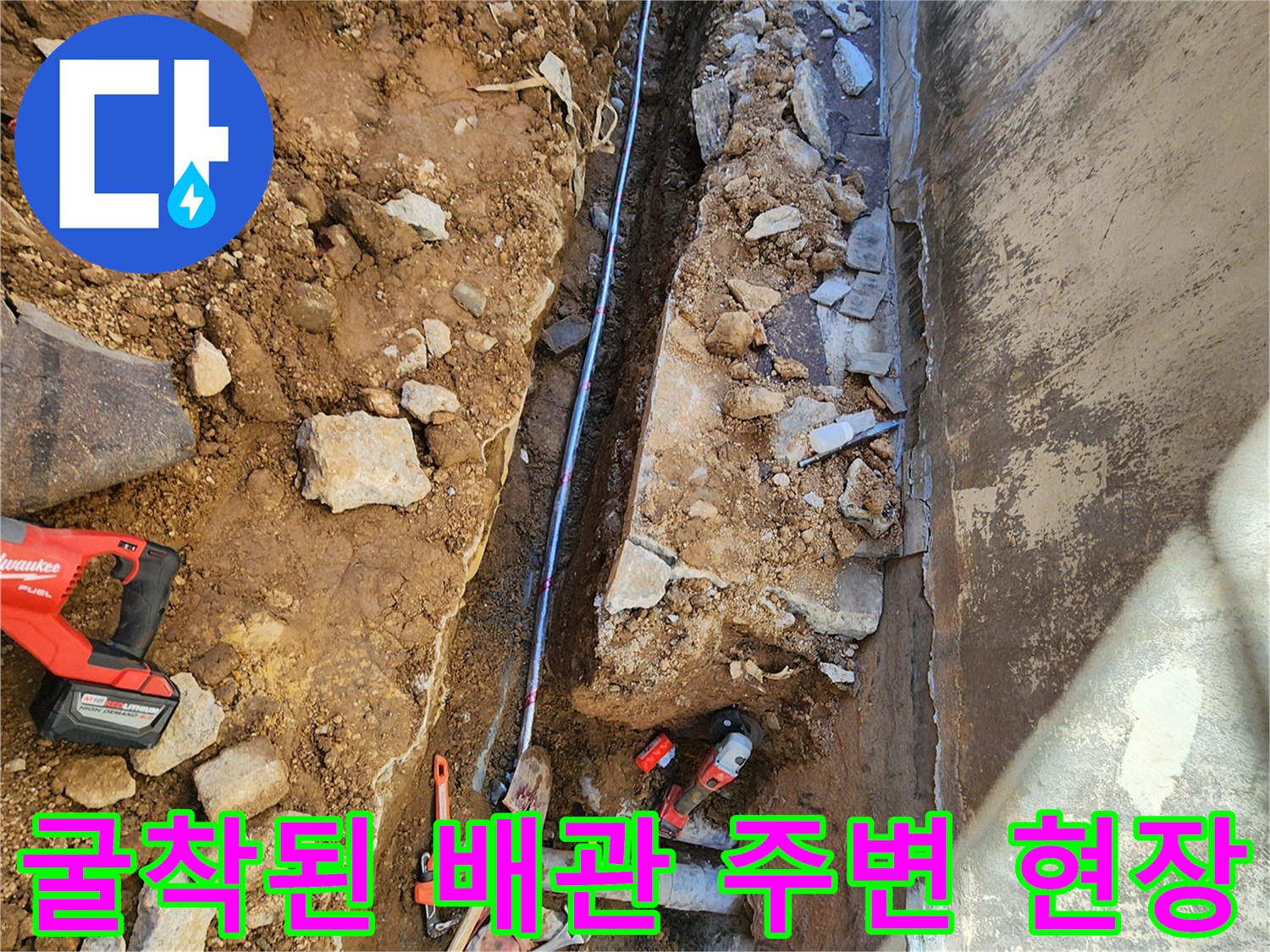 건물 외벽 하단 흙과 콘크리트를 제거하여 드러난 노후 배관의 모습