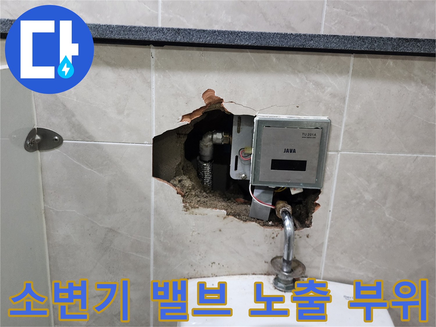 파손된 타일 사이로 보이는 소변기 자동 세척 장치와 급수 배관