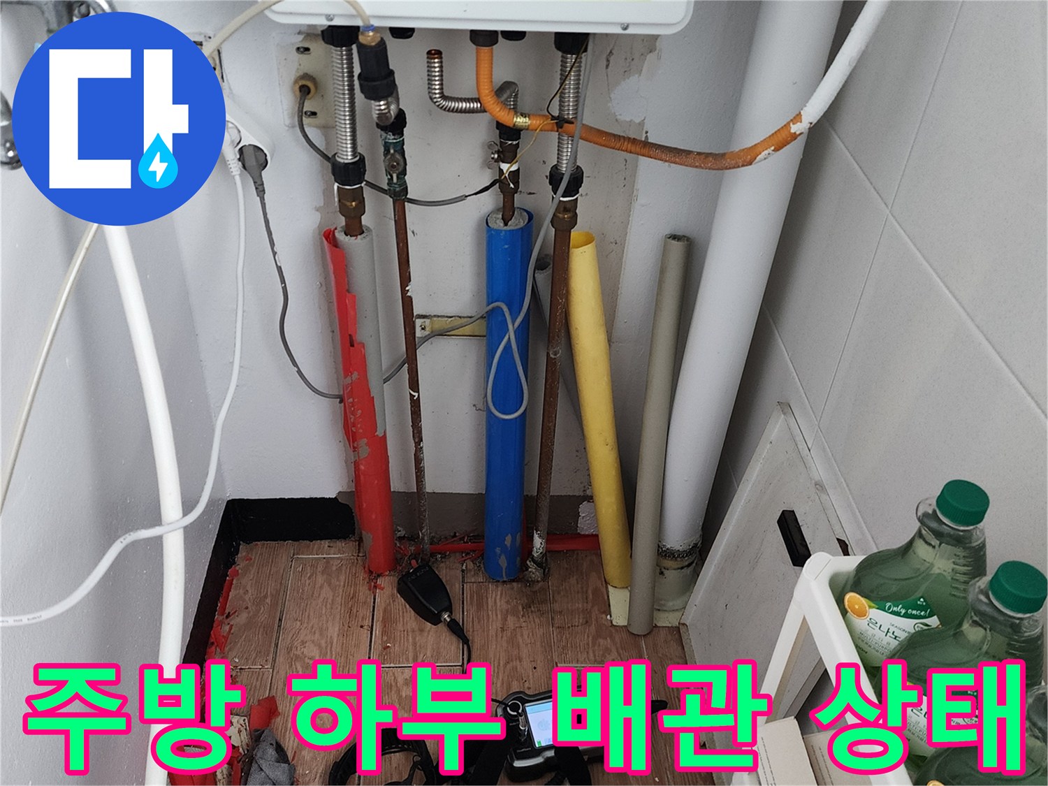 다양한 색상의 배관들이 연결된 주방 싱크대 하단 작업 모습