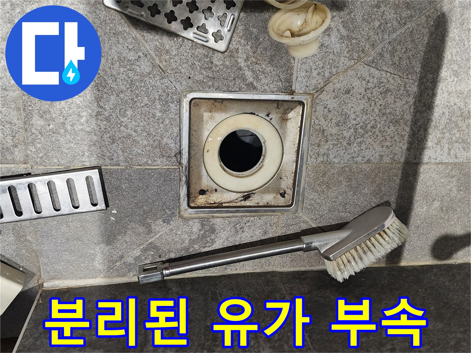욕실 바닥에서-탈거된 유가 부속과 청소용 솔의 모습