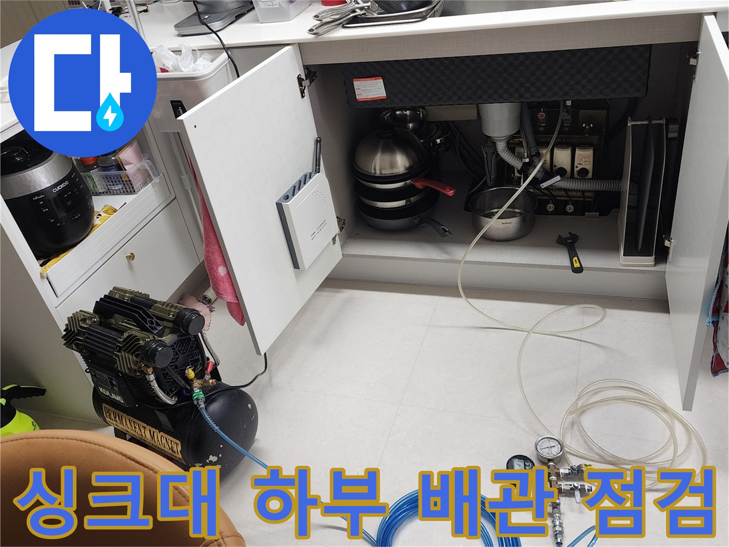 주방 싱크대 밑 배관 연결 부위를 공압 테스트 장비로 확인하는 모습입니다.