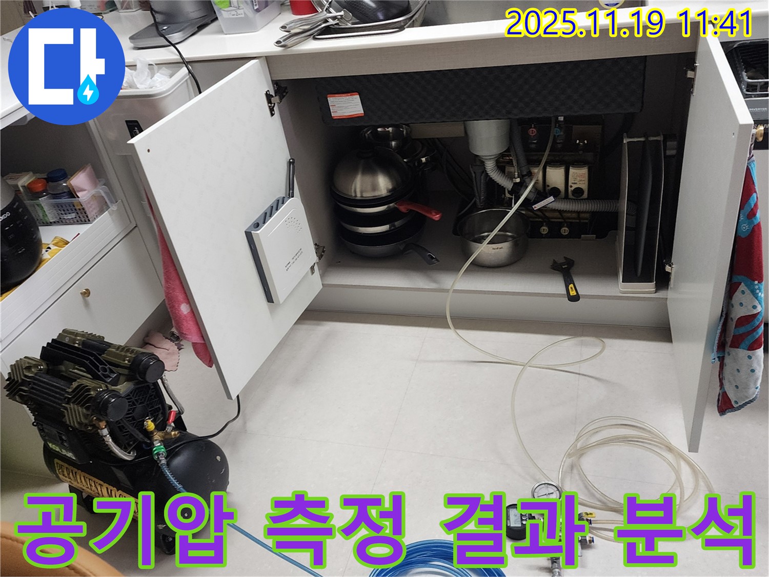 포천 내촌 누수 현장 - 싱크대 하부에서 공기압 측정 결과를 꼼꼼하게 분석하는 모습입니다.