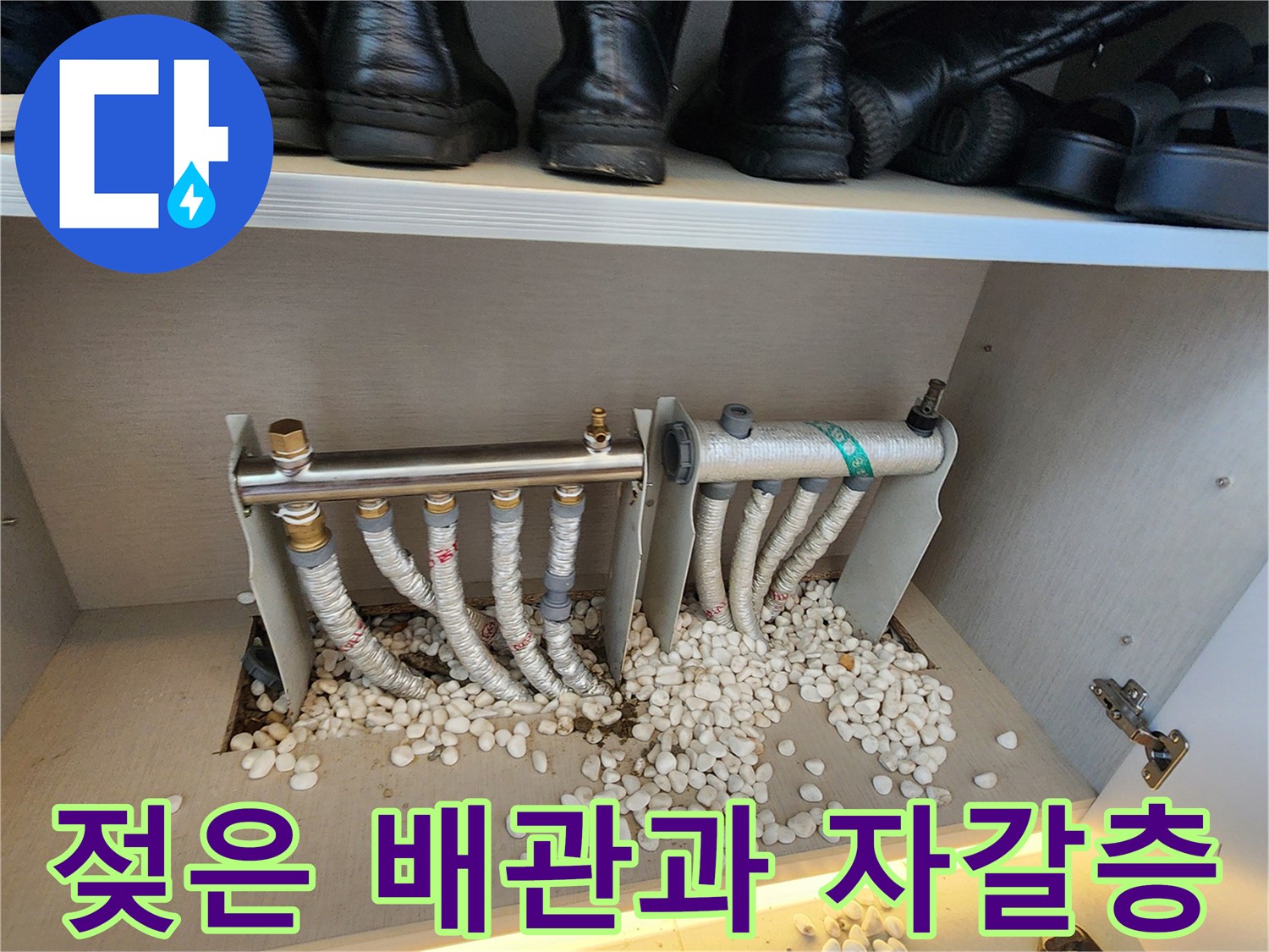 분배기 하단 배관 연결 부위와 물에 젖은 자갈의 근접 사진입니다.