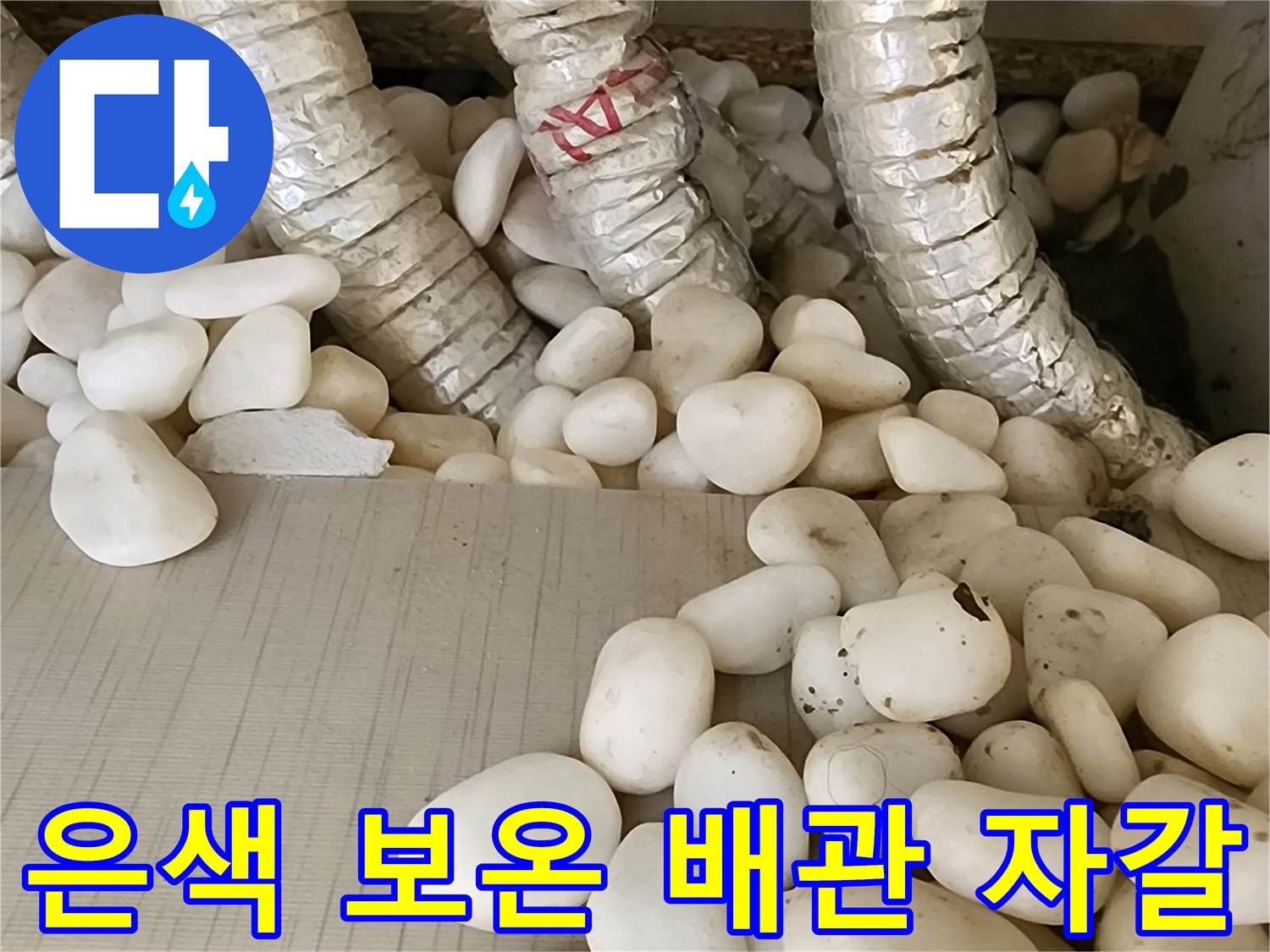 자갈 사이에 놓인 은색 배관 - 누수 지점 확인을 위한 근접 촬영