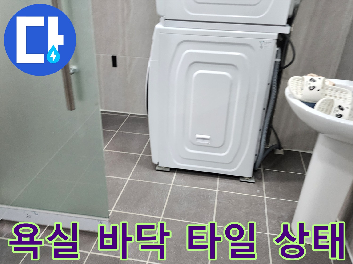 세면대와 세탁기가 배치된 욕실 바닥의 타일 줄눈을 보여줍니다.