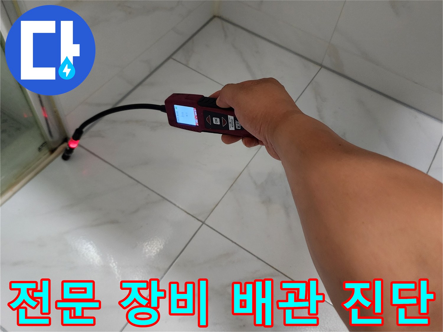 가스 탐지기 노즐을 타일 틈새에 대고 누수 반응을 살피는 작업 장면입니다.
