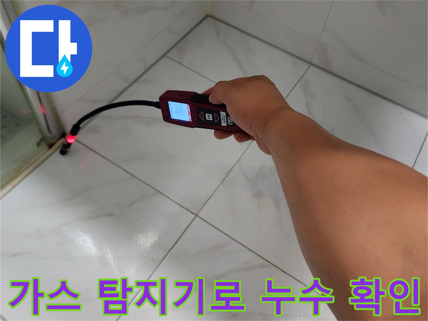 화이트 대리석 패턴 타일에 가스 탐지기를 밀착하여 검사하는 모습