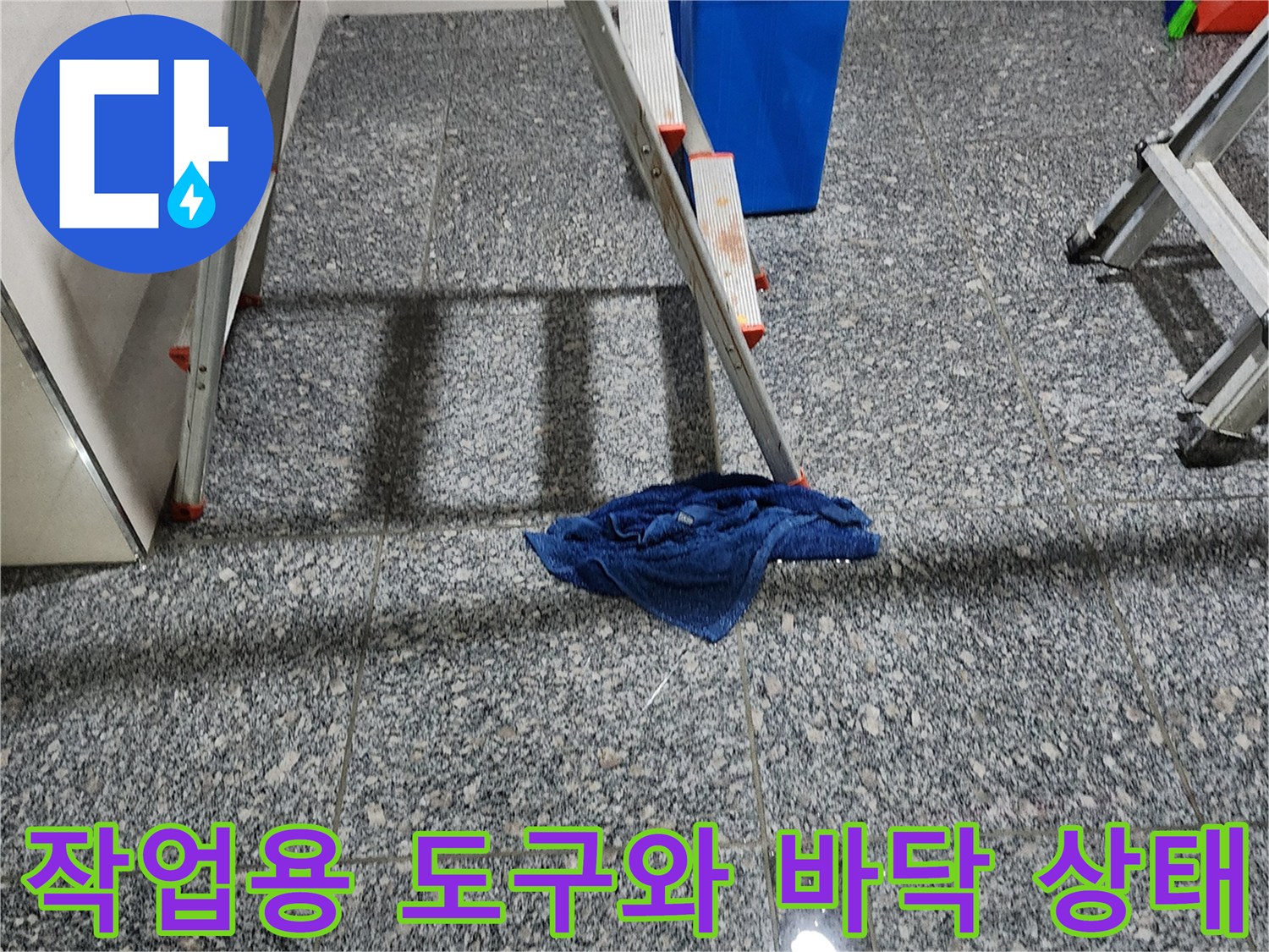 회색 타일 바닥에 놓인 파란 양동이와 작업용 걸레
