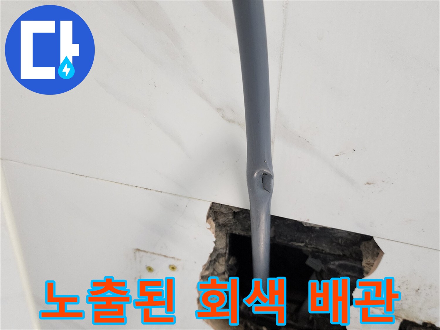 벽 내부를 파내어 확인한 회색 배관과 주변 마감재 상태