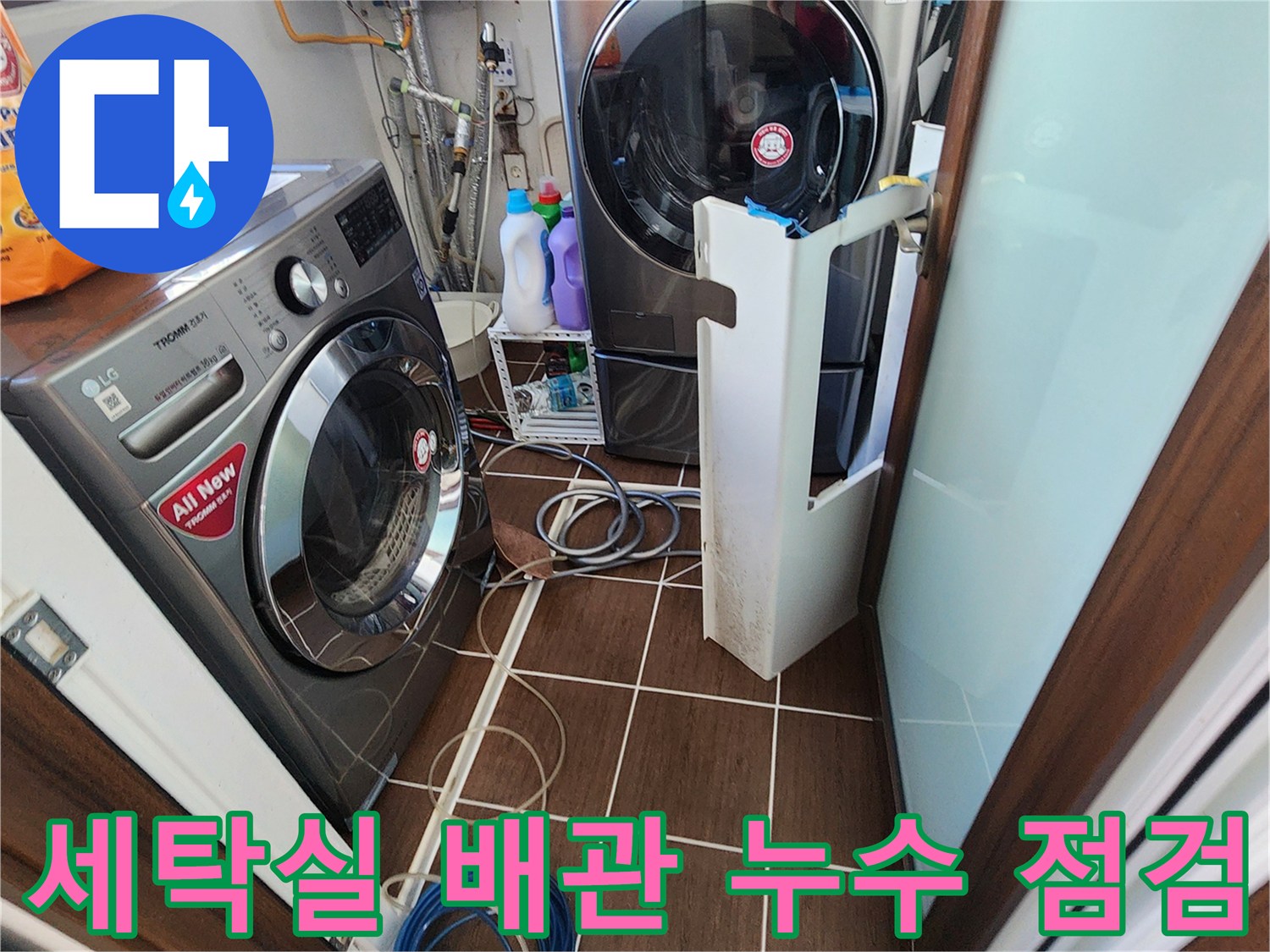 세탁기 뒤편의 급수 및 배수 호스들이 연결된 다용도실 현장입니다.
