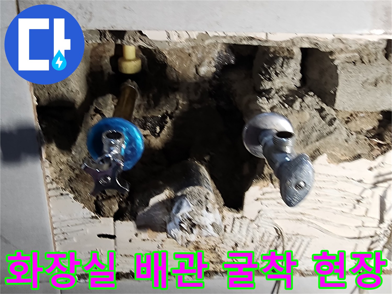 화장실 타일을 제거하고 드러난 배관의 파손 상태를 보여주는 사진입니다.