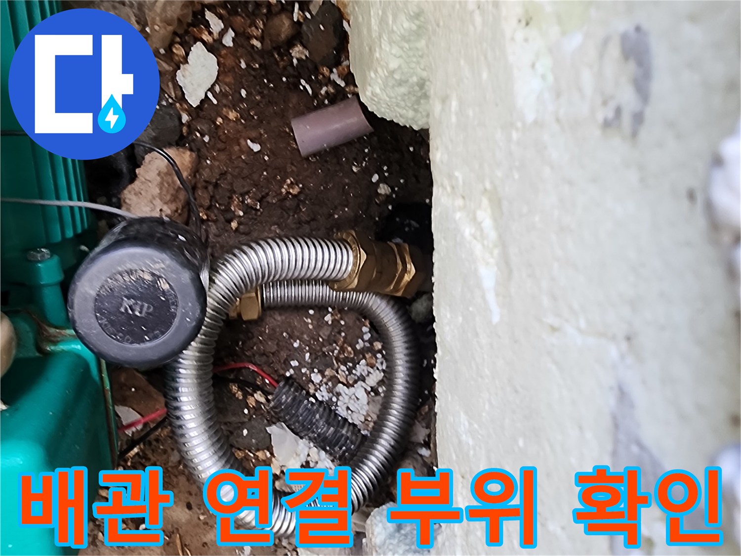외벽 하단 흙 속의 배관 연결 부위와 보수 장비 모습