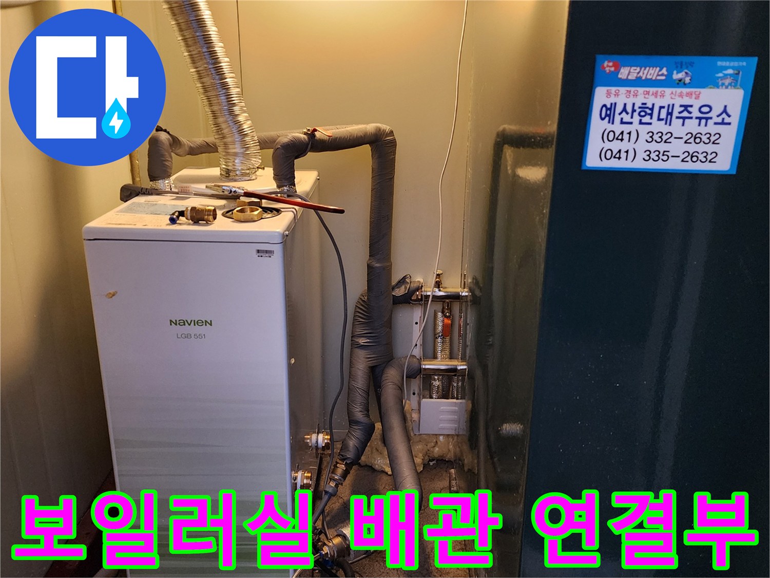 보일러 하단에 복잡하게 연결된 배관과 은색 연통 모습