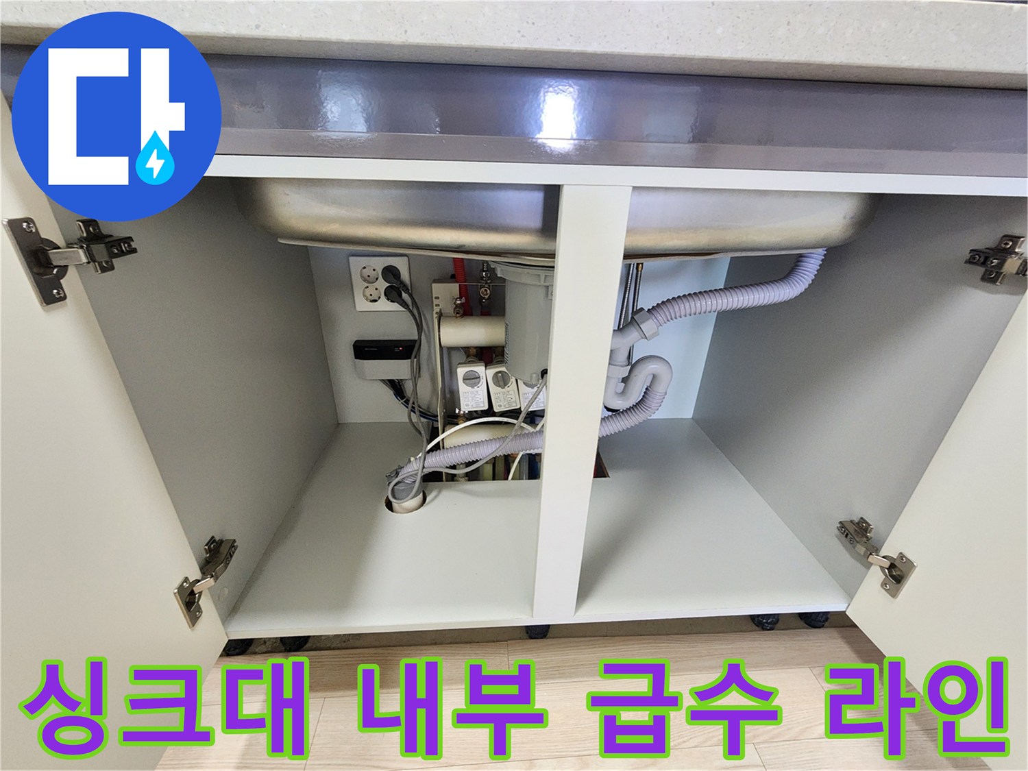 주방 하부장 내부의 배수 호스와 벽면 급수 밸브 상세 촬영