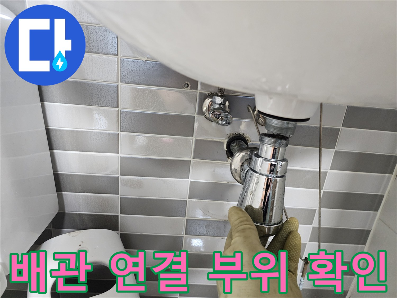 세면대 아래 배관의 결합 상태를 점검하고 있습니다.