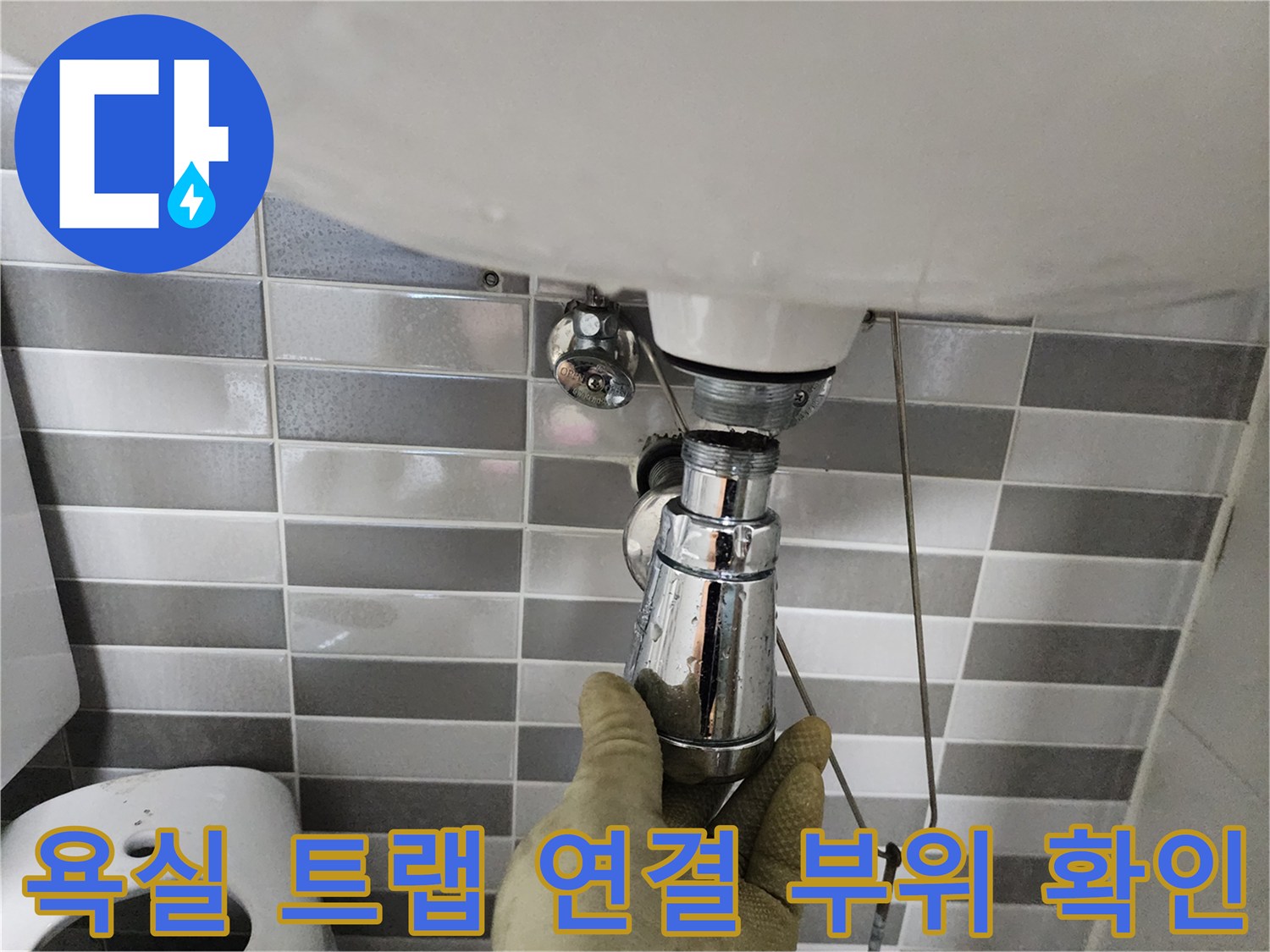 세면대 하단 크롬 배관의 연결 상태를 점검하는 현장 사진입니다.