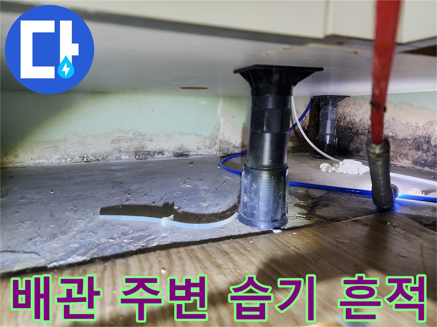 싱크대 하단 배관과 습기로 변색된 벽면의 근접 사진