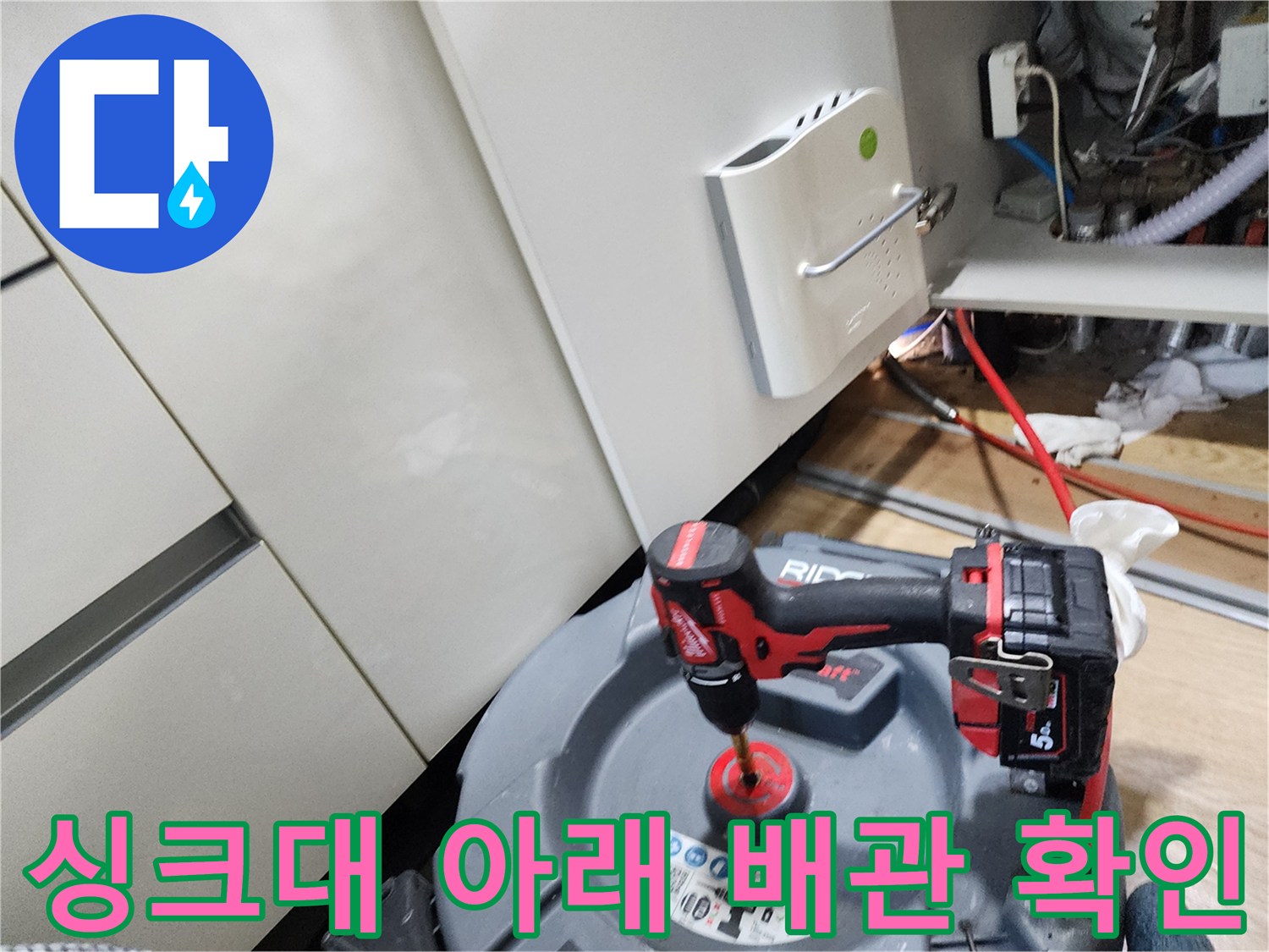 싱크대 하부의 배관 연결 부위와 주변 환경을 점검하는 모습입니다.