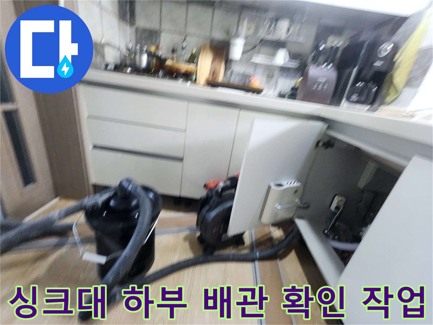 주방 싱크대 아래쪽의 배관 상태를 점검하기 위해 장비를 사용하는 모습