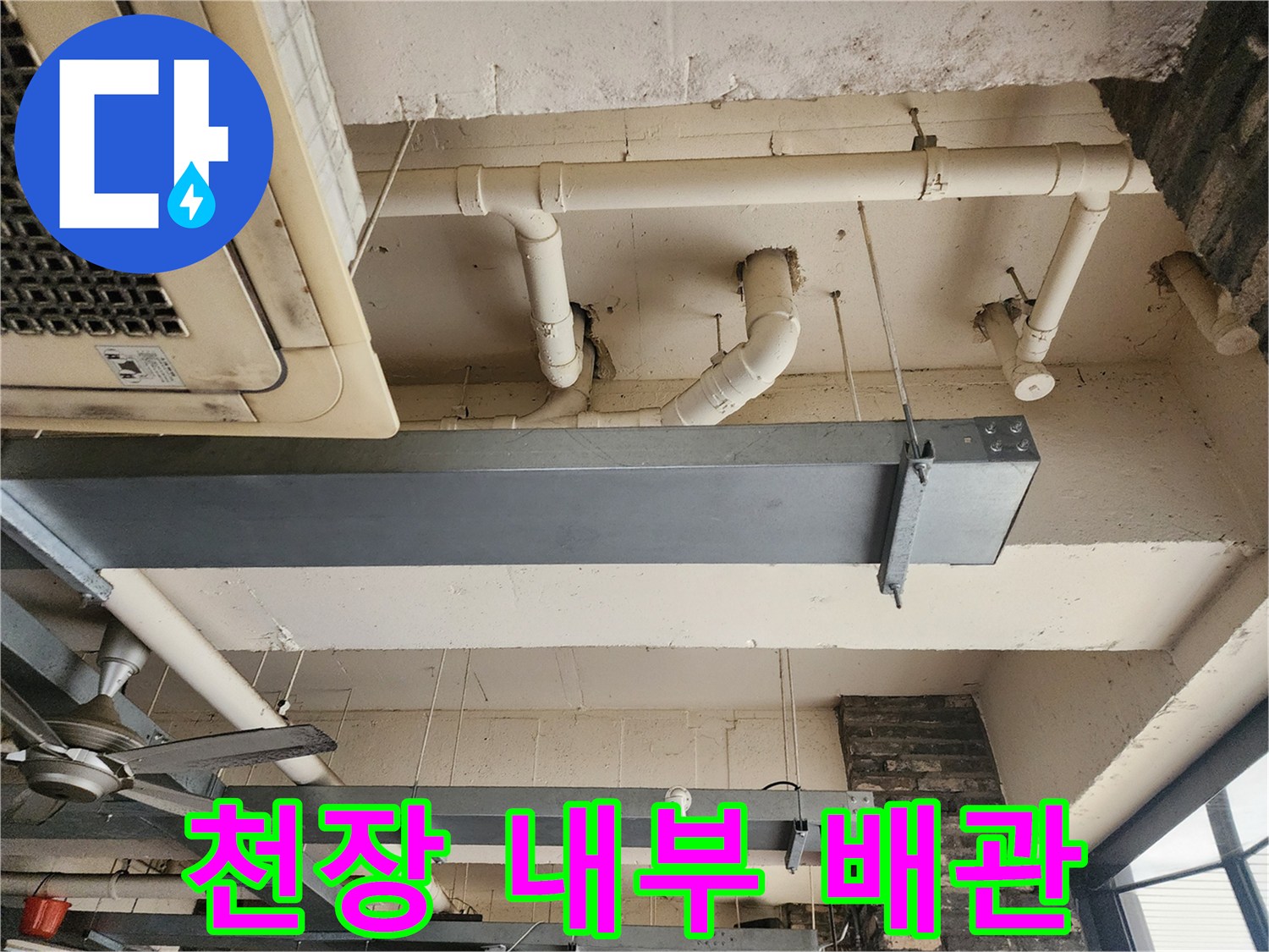 금속 프레임과 흰색 PVC 배관이 복잡하게 얽힌 천장 구조물