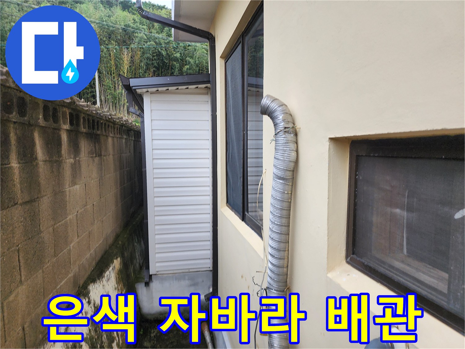 건물 창문 옆에 설치된 굴곡진 은색 배관의 모습