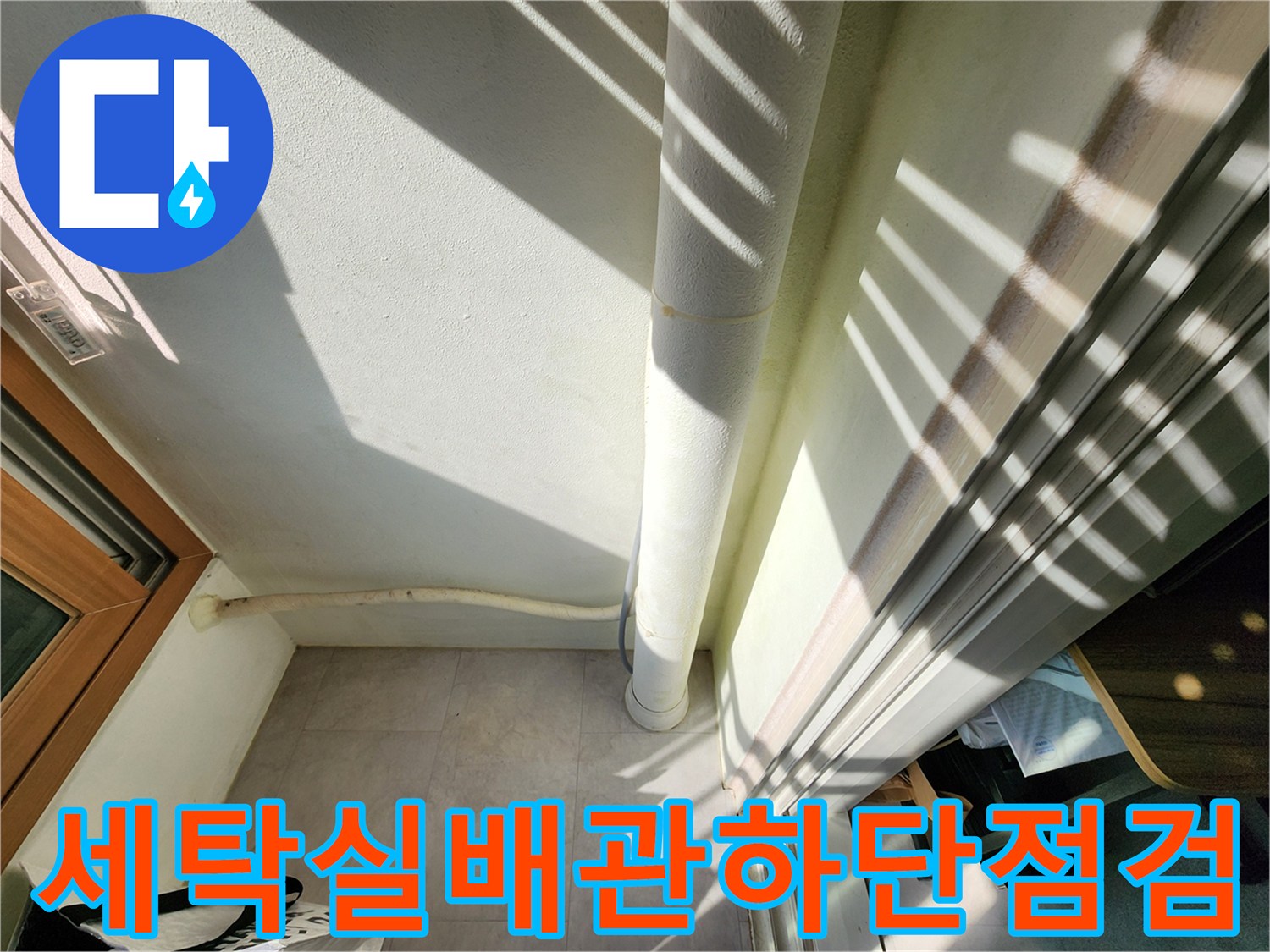 수직으로 내려오는 흰색 배관과 바닥 타일 경계 부위