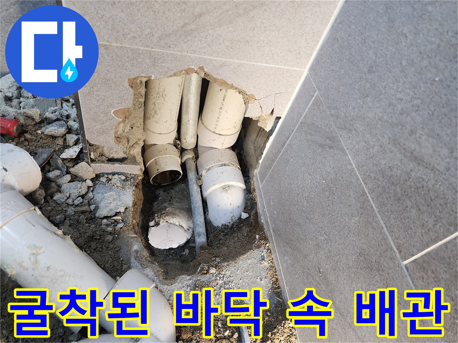 타일 아래 젖어 있는 흙과 노출된 하수 배관 연결부