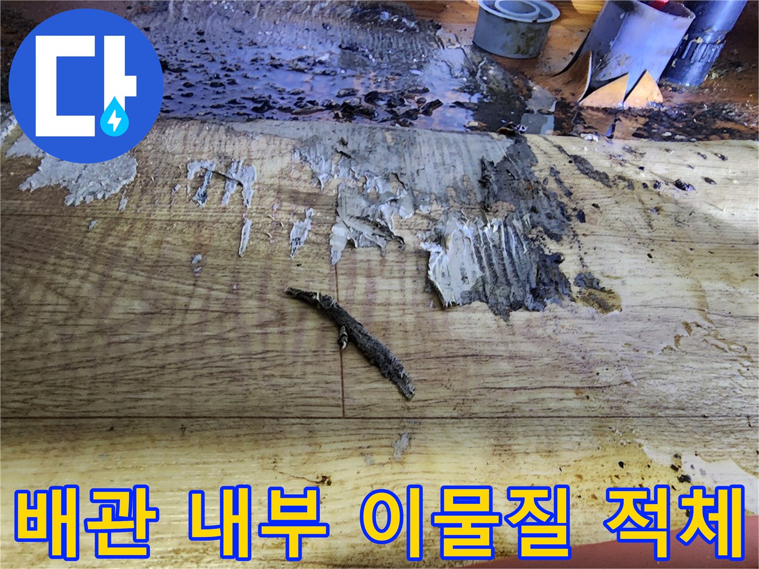 나무 판재 위에 쌓인 검은색 배관 오물과 슬러지