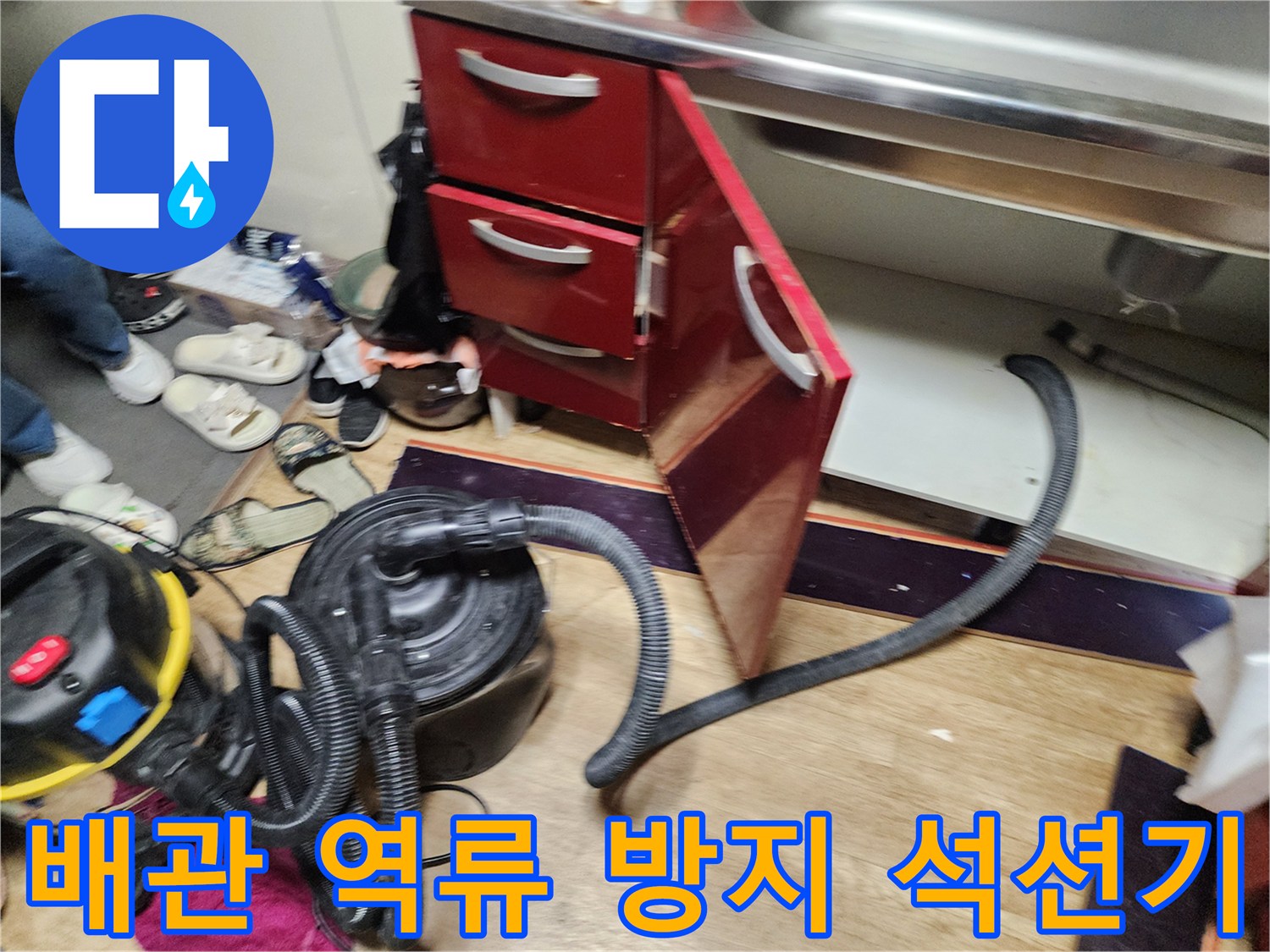 싱크대 하부장 아래 배관 청소를 위해 준비된 석션 장비와 호스 연결