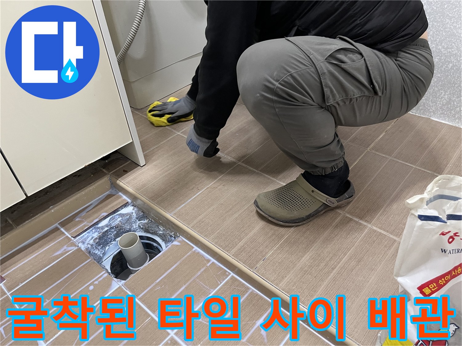 타일을 걷어내고 드러난 흰색 배수관 연결 부위의 모습입니다.