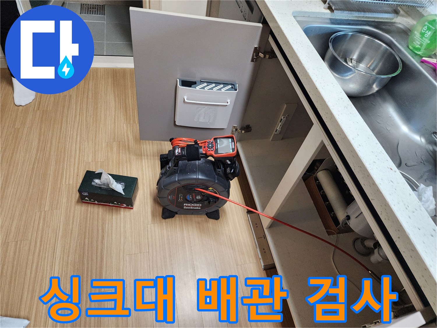 싱크대 하부장 내부의 배관 상태를 확인하기 위해 내시경 장비를 사용 중인 현장