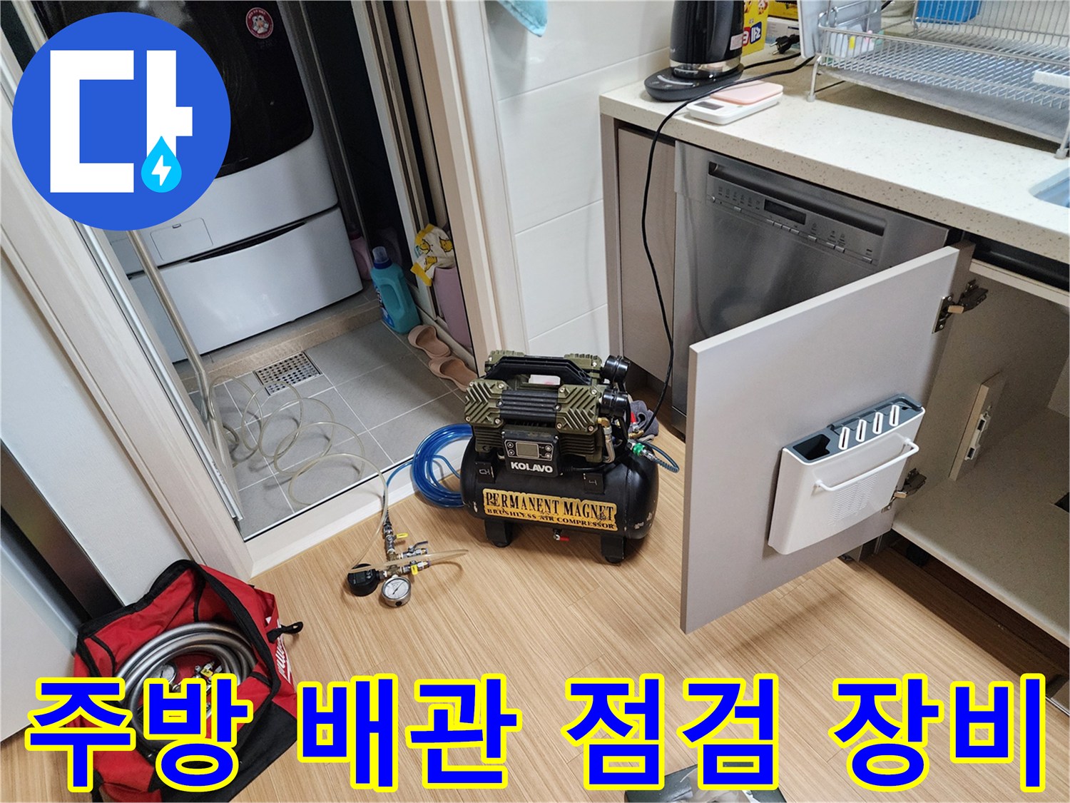 싱크대 하부장 옆에 놓인 배관 압력 체크용 컴프레셔와 게이지 장비