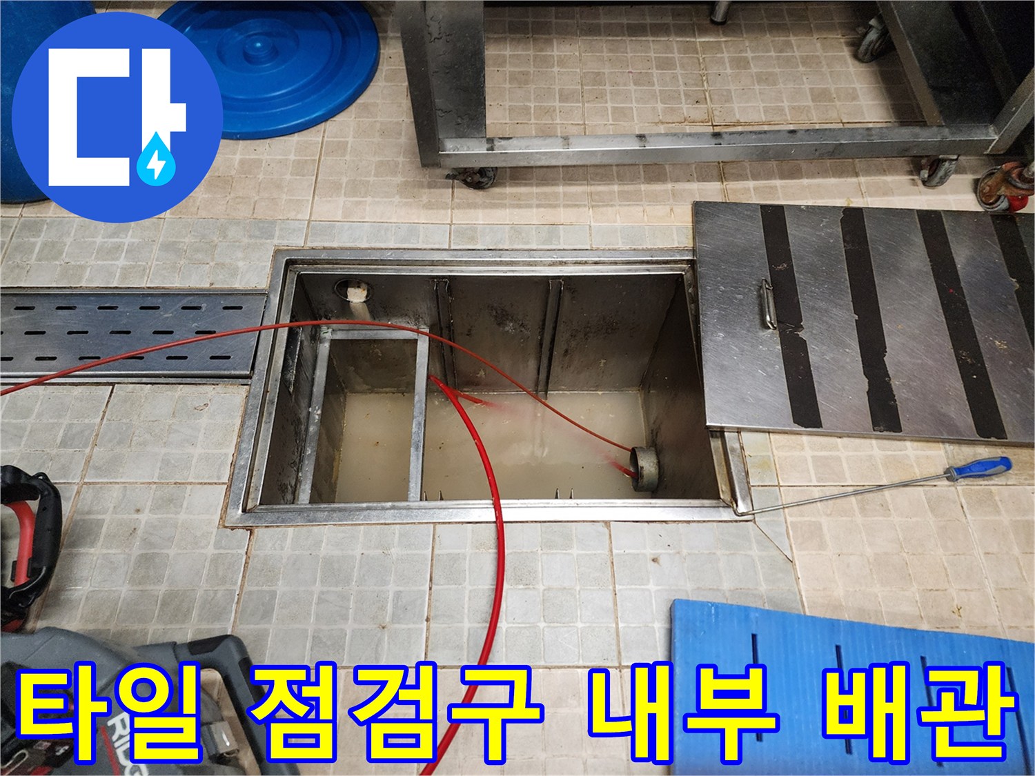 타일로 마감된-주방 점검구 내부의 노출된 배관과 장비