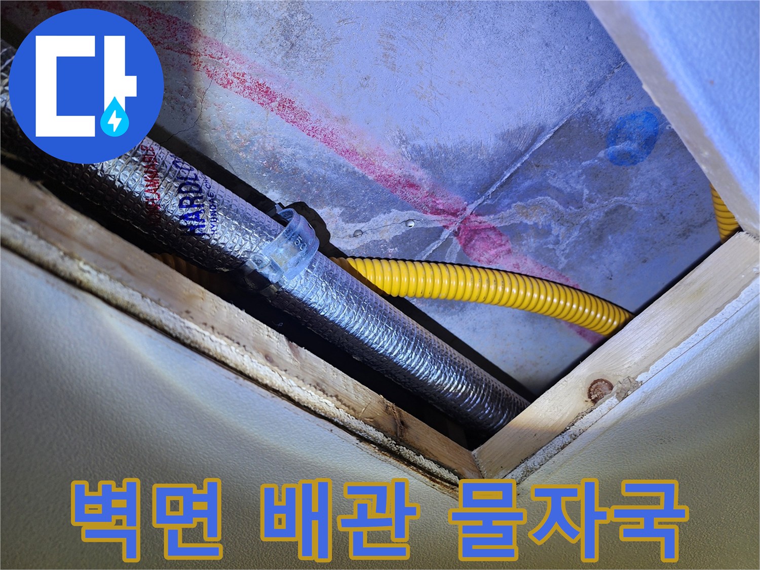 노란색 배관 뒤편 벽면에 나타난 붉고 어두운 습기 자국