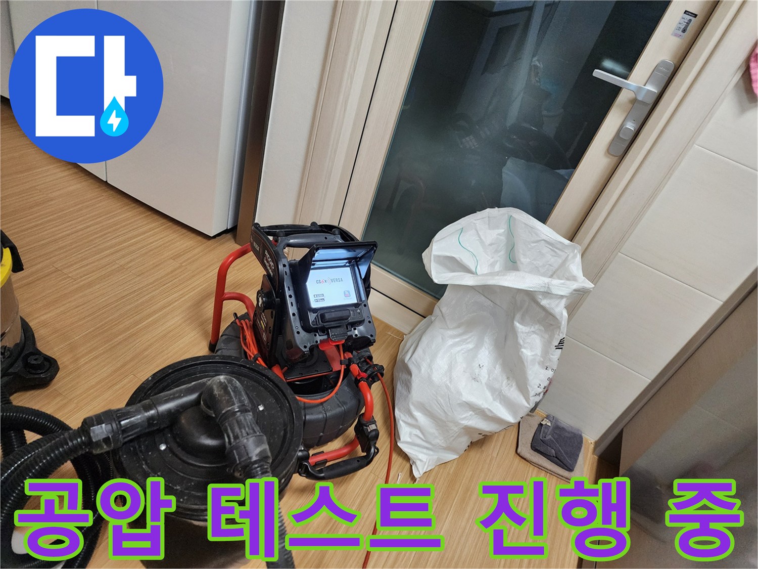 싱크대 하부 배관에 공압 장비를 연결하여 압력을 측정하는 장면입니다.