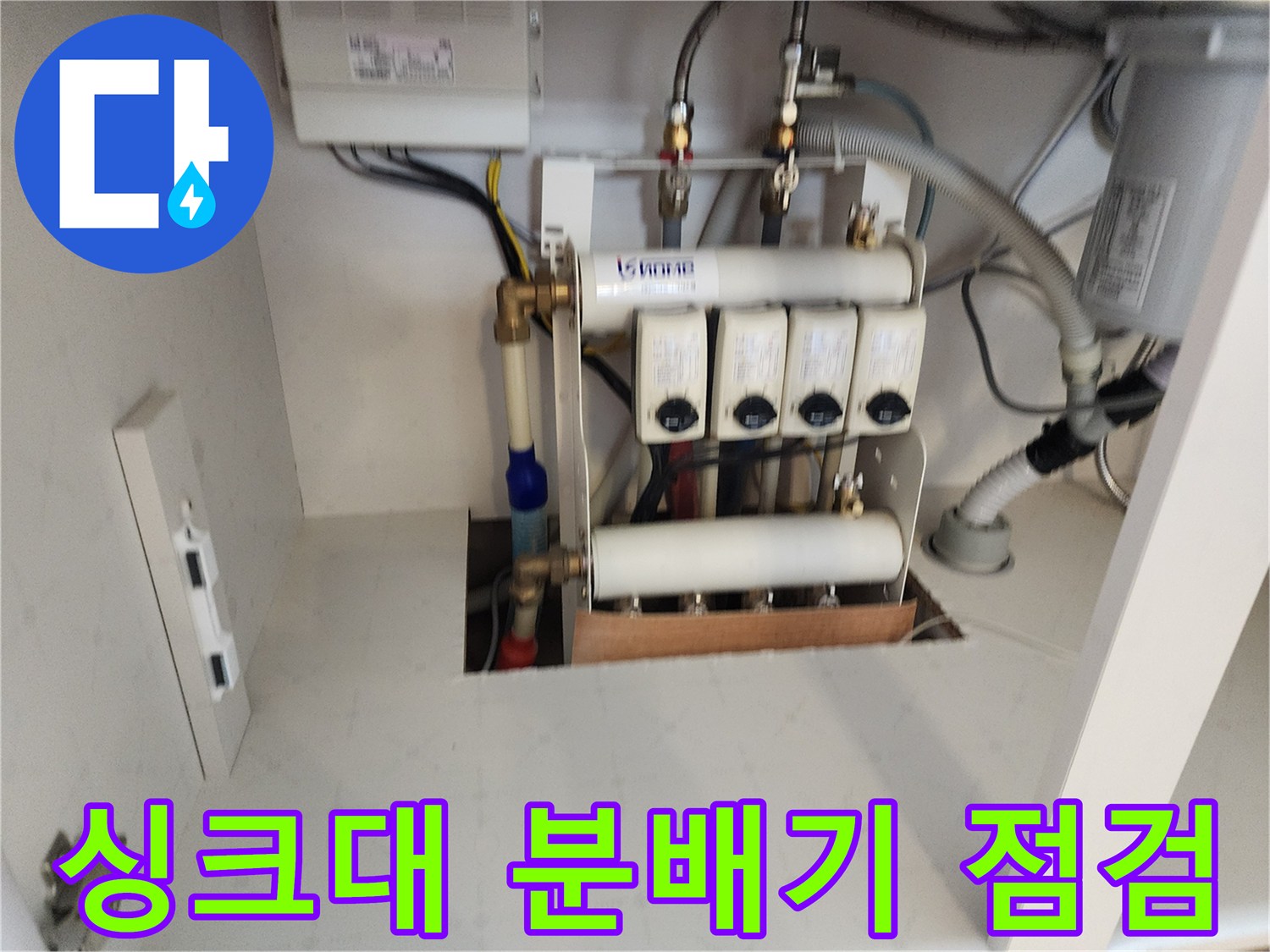 싱크대-하부장-내부의-수도-분배기와-배관-상태를-확인하는-모습