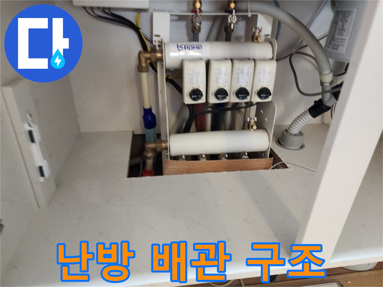 싱크대 하부장에 노출된 난방 분배기 밸브와 급수 배관의 모습입니다.
