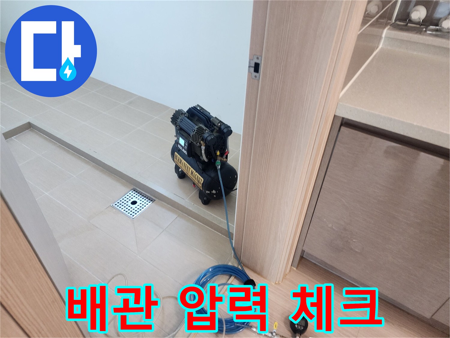 배수구 근처 타일 바닥에 배치된 공압 테스트 장비와 연결 호스