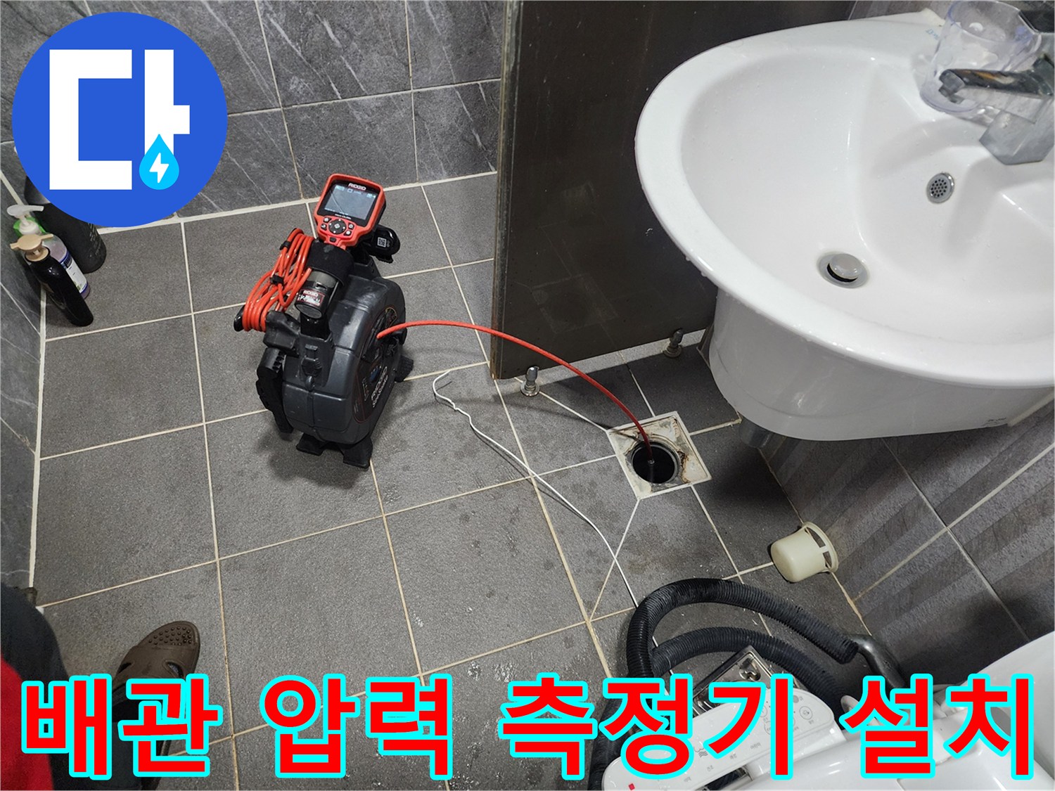 화장실 바닥 타일 위 배수구와 연결된 공압 테스트 장비
